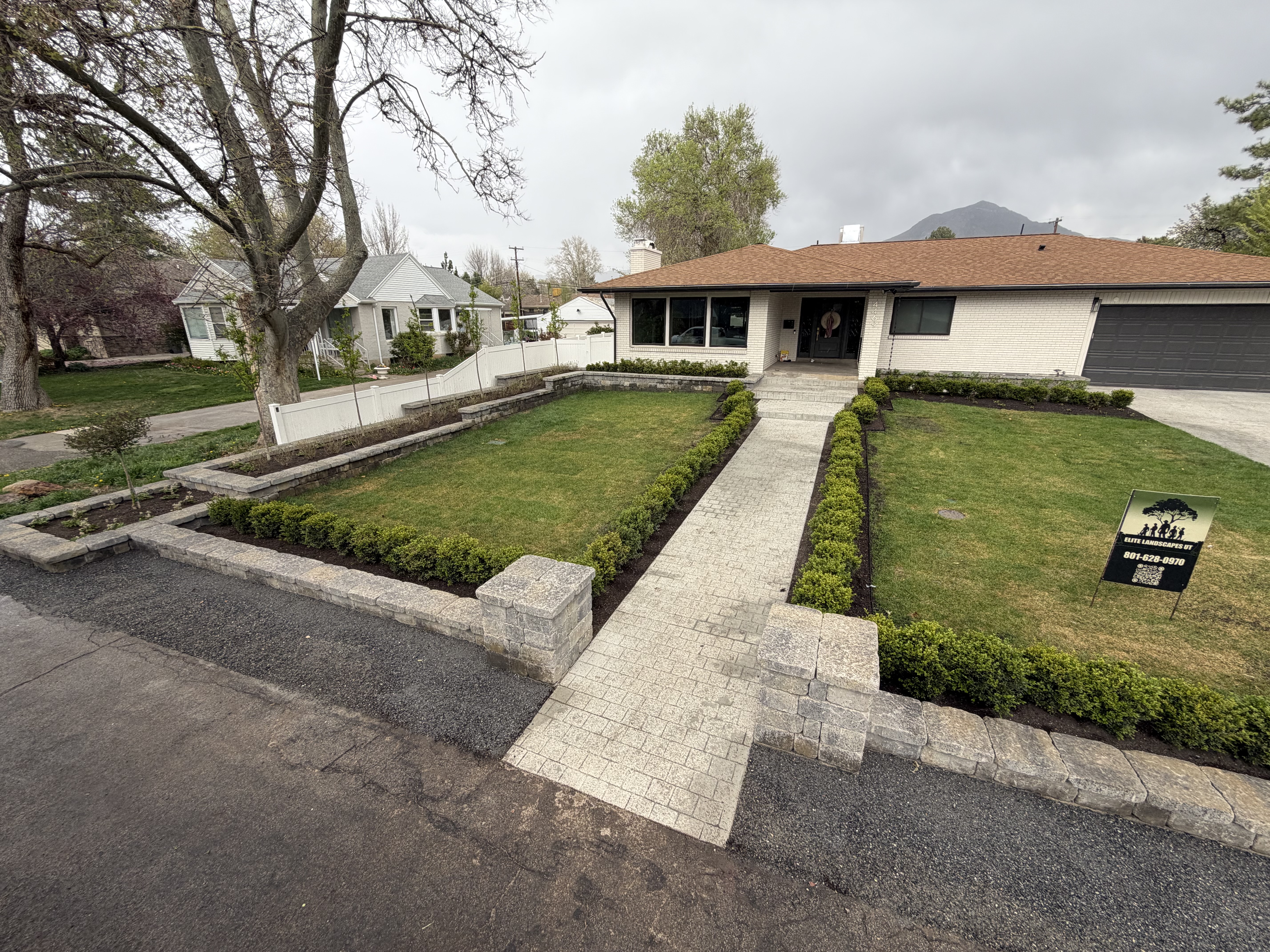 Established landscape with hedge lined entry walkway and paver columns