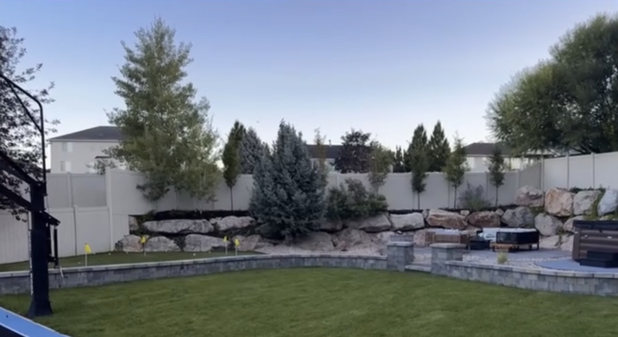 Outdoor living space with putting green, fire pit, and boulder backdrop