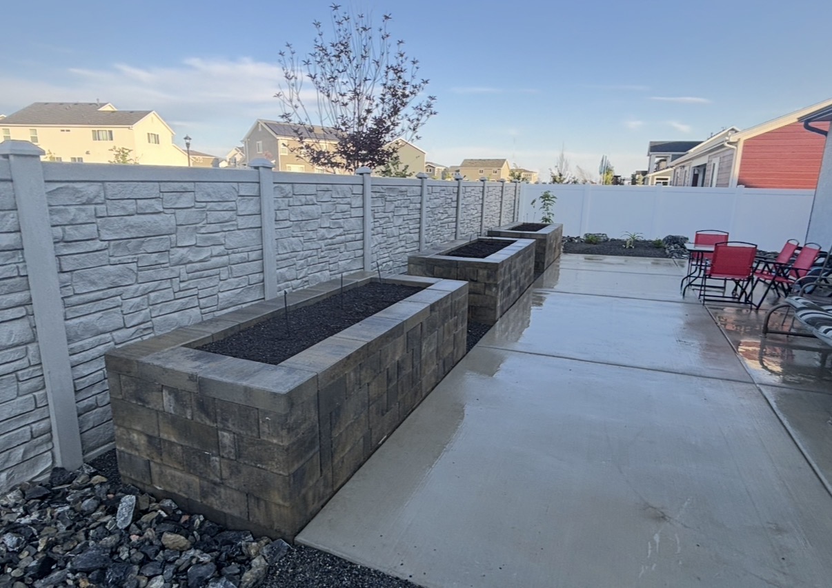 Brick block planter walls lining a backyard concrete patio