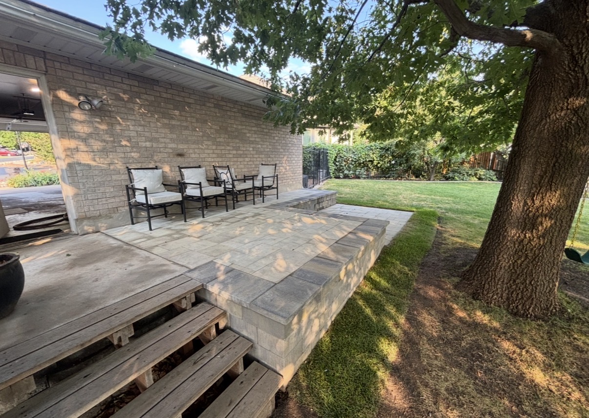 Paver patio next to brick home with seating