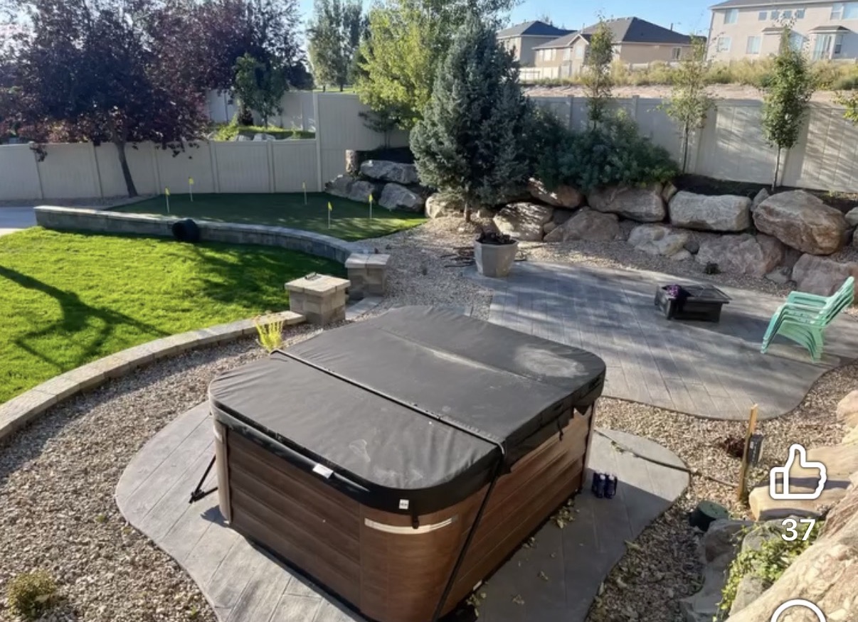 Backyard hot tub on stamped patio with putting green