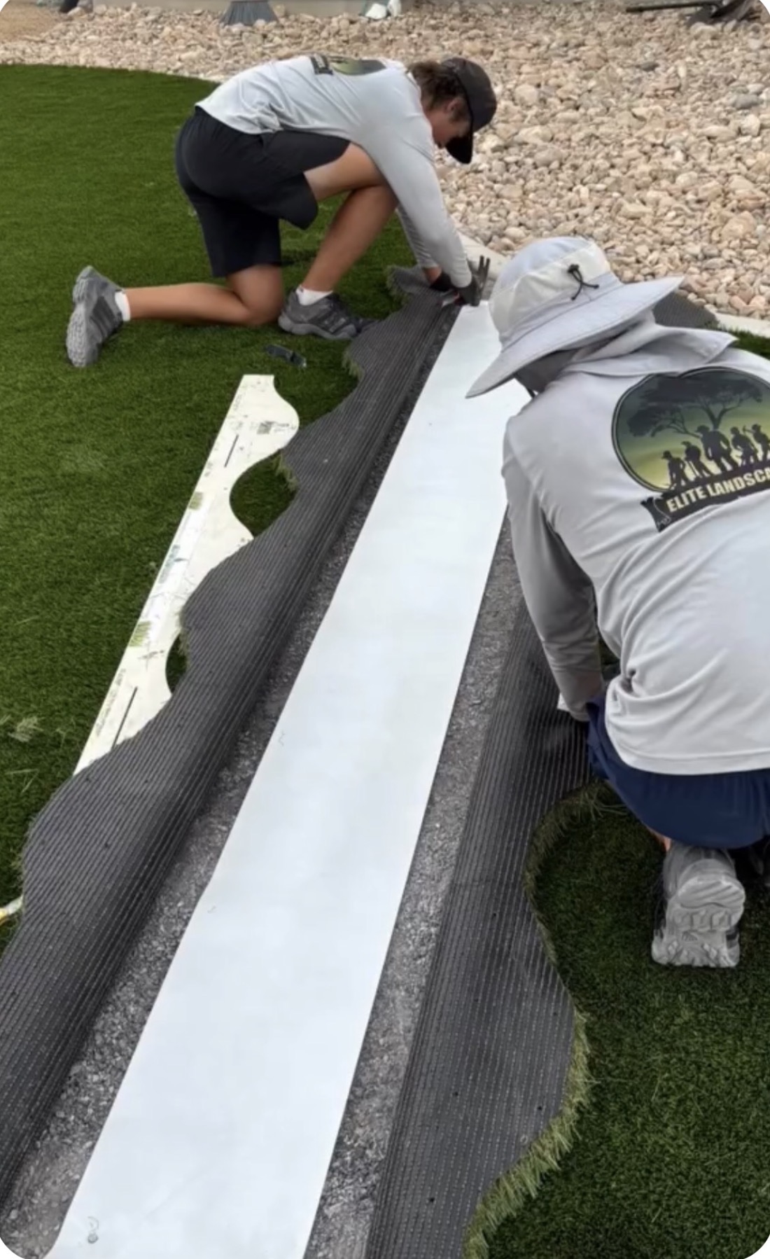 Crew seaming a turf install with Elite Landscapes logo on shirt