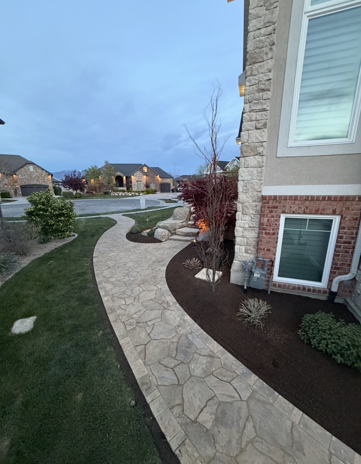 Curved paver walkway by brick home