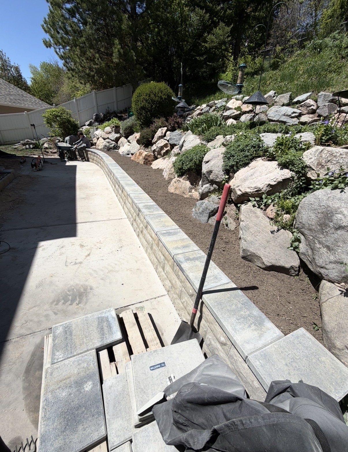 Block wall in progress against a boulder slope