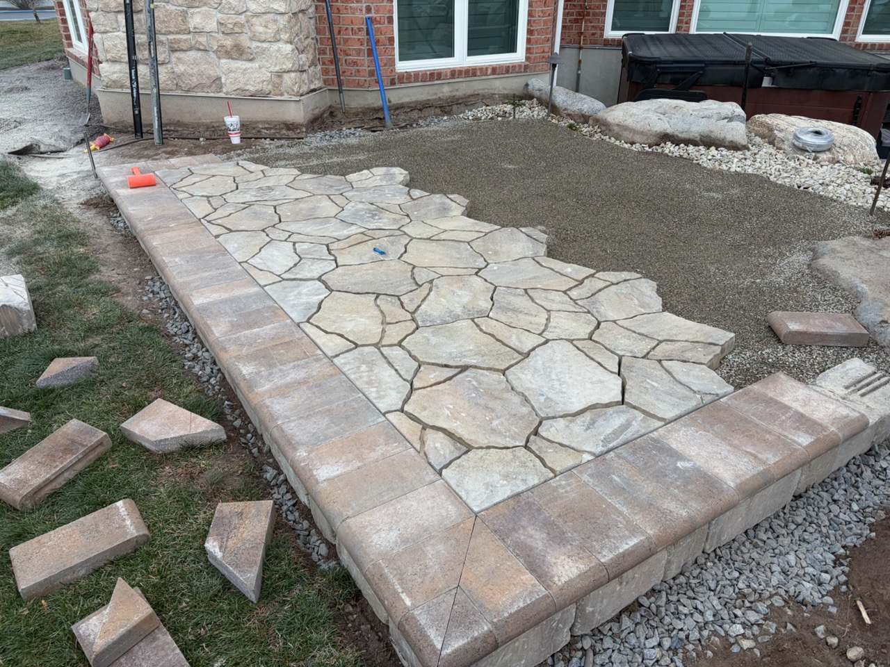 Raised flagstone paver patio with brick coping beside a hot tub